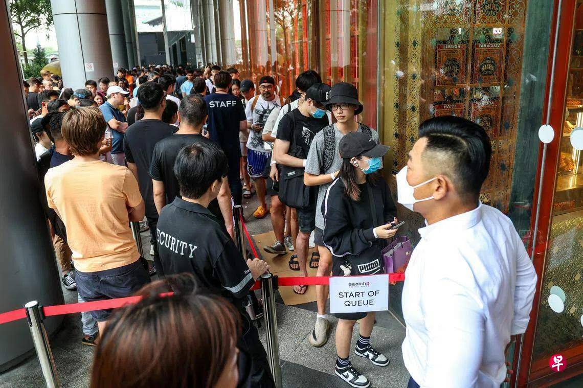 Singapore Swatch queue with 'Start of Queue' sign, security guard, masked customers in line